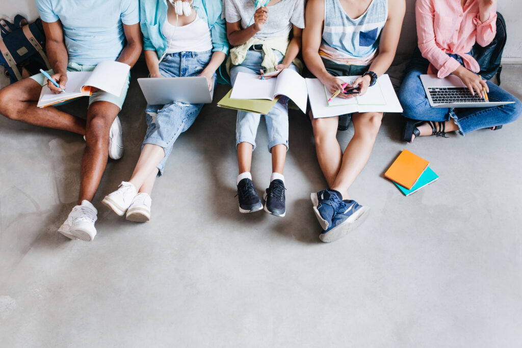 Young people with laptops sitting together on the floor